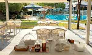 En utendørs område med bord og stoler, hvor bassengområdet er synlig i bakgrunnen. (AI-generert tekst)