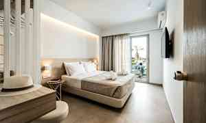 Et hotellrom med en dobbeltseng, en TV og en balkongdør. Skrivebord med hatt og stol. (AI-generert tekst)