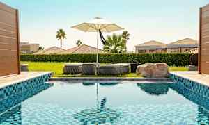 Et svømmebasseng med solsenger og en parasoll i bakgrunnen. (AI-generert tekst)