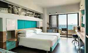 Moderne hotellrom med dobbeltsenger og utsikt over havet fra balkongen. (AI-generert tekst)