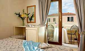 Hotellrom med vindu ut mot en balkong, bord med champagne og utsikt over bygning. (AI-generert tekst)