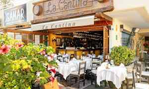 En restaurant med uteservering dekorert med hvite duker og blomstrende planter. (AI-generert tekst)