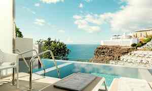 Et privat basseng med havutsikt og nærliggende hotellbygninger. (AI-generert tekst)