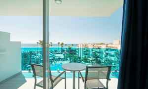 Utsikt fra en balkong med to stoler og et bord mot havet og et hotellbasseng. (AI-generert tekst)