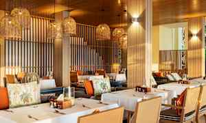 En restaurant med dekkede bord og hengende lampeskjermer i flettet design. (AI-generert tekst)