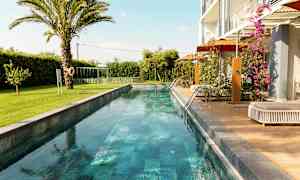 En lang smal basseng omgitt av grøntområder og en moderne bolig. (AI-generert tekst)