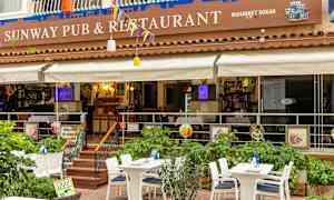 En utendørs terrasse av en restaurant med bord og stoler. (AI-generert tekst)