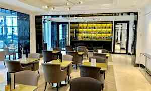 En moderne kafé med elegante bord og stoler samt en velutstyrt bakspeil bak. (AI-generert tekst)