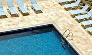 Bilde av et klarblått basseng med solsenger plassert på en steinlagt flate rundt. (AI-generert tekst)