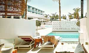 Solstoler ved et basseng med moderne arkitektur i bakgrunnen. (AI-generert tekst)