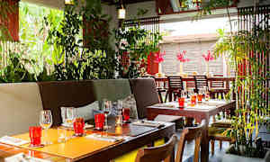 Et innbydende restaurantområde med planter, trebord og dekorative glass. (AI-generert tekst)