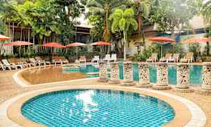 Et utendørs svømmebasseng omgitt av palmer og solsenger med parasoller. (AI-generert tekst)