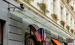 Hotellfasade med inngang dekorert med blomsterpotter og flagg. (AI-generert tekst)