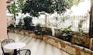 Uteplass med bord, stoler og grønne planter. (AI-generert tekst)