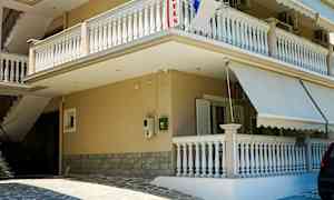 Bygning med balkonger og markiser ved en steinbelagt inngang. (AI-generert tekst)