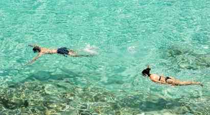 To personer snorkler i klart turkis vann. (AI-generert tekst)