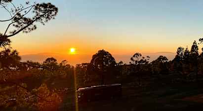 Bilde av en solnedgang over en skog med et kjøretøy i forgrunnen. (AI-generert tekst)