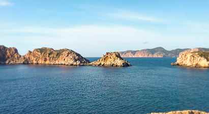 Kystlandskap med steinete øyer i havet under en klar blå himmel. (AI-generert tekst)