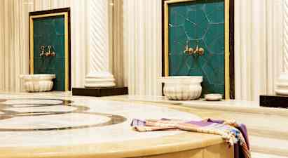 Bilde av et tradisjonelt hamam med marmoroverflater og vannkraner. (AI-generert tekst)