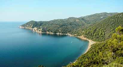 En kystlinje med en bukt omgitt av grønne fjell og klart blått hav. (AI-generert tekst)