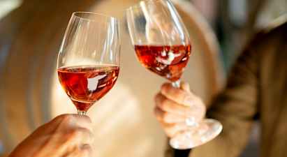 To glass med rosévin holdes opp. (AI-generert tekst)