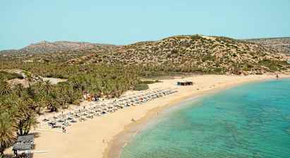 Sandstrand med turkis hav, solsenger og parasoller. Bakgrunn med vegeterte fjell. (AI-generert tekst)