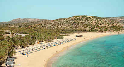 Sandstrand med turkis hav, solsenger og parasoller. Bakgrunn med vegeterte fjell. (AI-generert tekst)