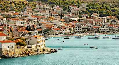 En kystby med hus tett ved vannkanten og båter i bukten. (AI-generert tekst)