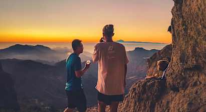 To personer ser på utsikten over fjellene ved solnedgang. (AI-generert tekst)