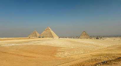 Bildet viser de store pyramidene i Giza omgitt av ørkenlandskap. (AI-generert tekst)
