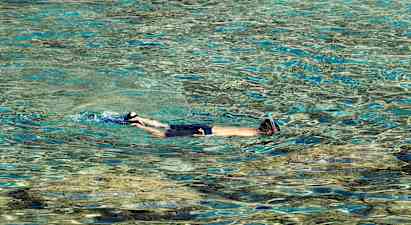 Person med snorkel svømmer i klart vann. (AI-generert tekst)