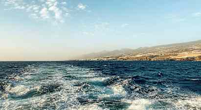 Havslandskap med bølger og kystlinje i bakgrunnen. (AI-generert tekst)