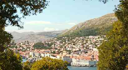 En utsikt over Dubrovnik med sin historiske bymur, omgitt av grøntområder. (AI-generert tekst)