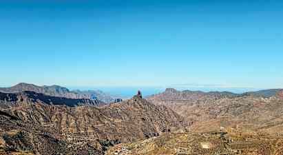 Landskap med fjell og en distinkt klippeformasjon under blå himmel. (AI-generert tekst)