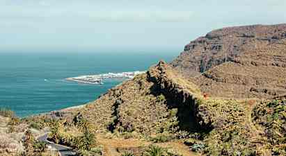 Utsikt over fjellandskap og kyst med hav og en havneanlegg. (AI-generert tekst)