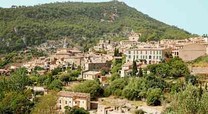 Bilde av en fjellandsby med flere steinhus omgitt av frodig vegetasjon. (AI-generert tekst)