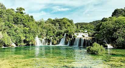 Et naturskjønt fossefall omgitt av frodig vegetasjon. (AI-generert tekst)