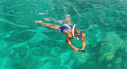 En person svømmer i klart vann med snorkelutstyr. (AI-generert tekst)