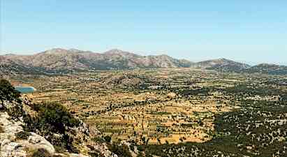 En vidstrakt dal omgitt av fjell med beitemarker og dyrkede åkere. (AI-generert tekst)