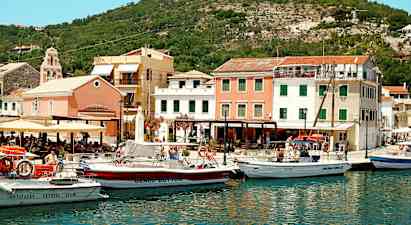 En havn med flere båter foran fargerike bygninger og omgitt av åser. (AI-generert tekst)