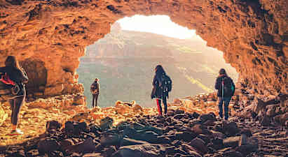 En gruppe mennesker utforsker en hule med utsikt over et fjellandskap. (AI-generert tekst)