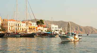 En havn med båter og bygninger, fjell ses i bakgrunnen. (AI-generert tekst)