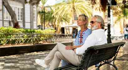 Personer sitter på en parkbenk i et bymiljø. (AI-generert tekst)