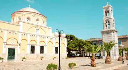 En gul bygning med kuppel og et klokketårn samt palmer og gatebelysning. (AI-generert tekst)