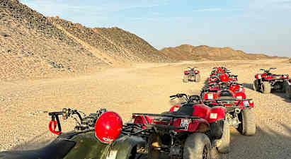 En rekke med ATV-er er parkert på en ørkenvei omgitt av sandete åser. (AI-generert tekst)