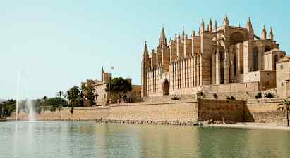 En katedral ved vannet med en fontene i forgrunnen. (AI-generert tekst)