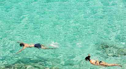 To personer snorkler i klart turkis vann. (AI-generert tekst)
