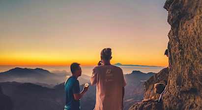 To personer ser på utsikten over fjellene ved solnedgang. (AI-generert tekst)