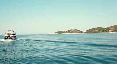 En båt kjører over et rolig hav med noen lave øyer i horisonten. (AI-generert tekst)