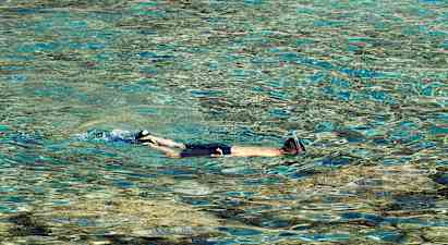 Person med snorkel svømmer i klart vann. (AI-generert tekst)